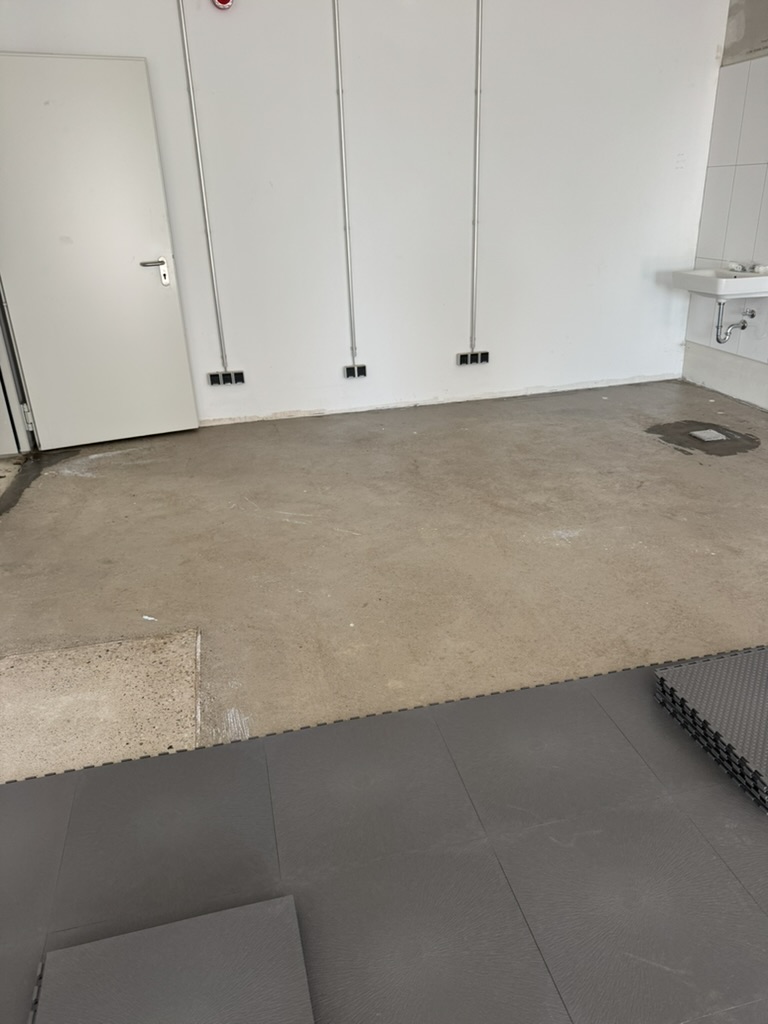 Verlegung dunkler Industriebodenplatten in einem Gewerberaum
