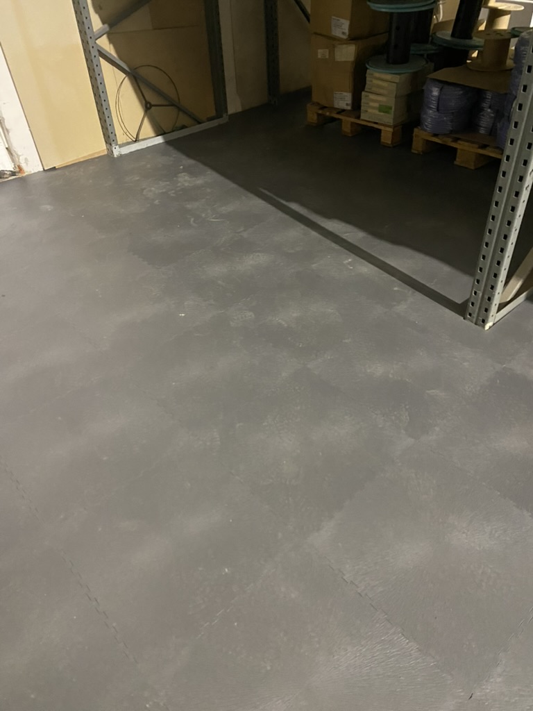 Fertig verlegte dunkle Bodenplatten unter Lagerregalen